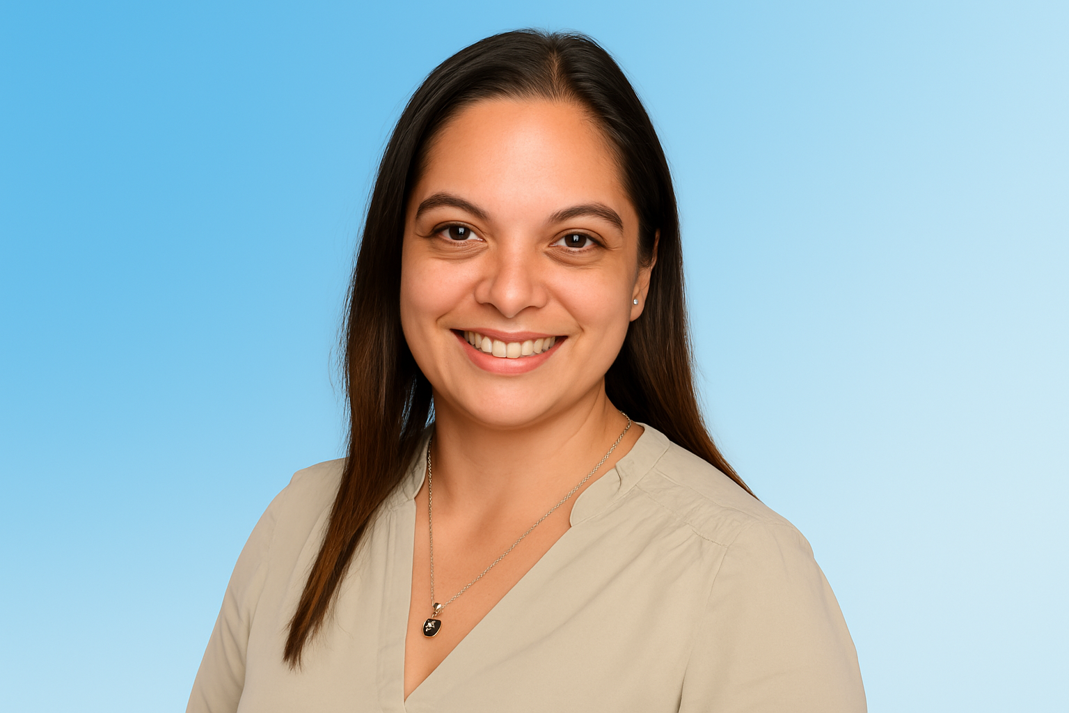 Headshot of a smiling woman with long dark brown hair, wearing a light sage green blouse and a heart-shaped necklace, set against a smooth gradient blue background.
