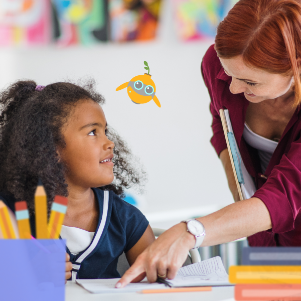 Young mixed heritage girl looking up at smiling red-headed teacher while completing EAL activities.