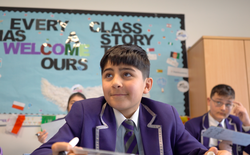 Smiling male student in school uniform listens in class